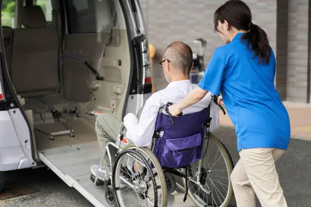 Un accompagnant aide un usager en fauteuil roulant à monter dans un véhicule adapté